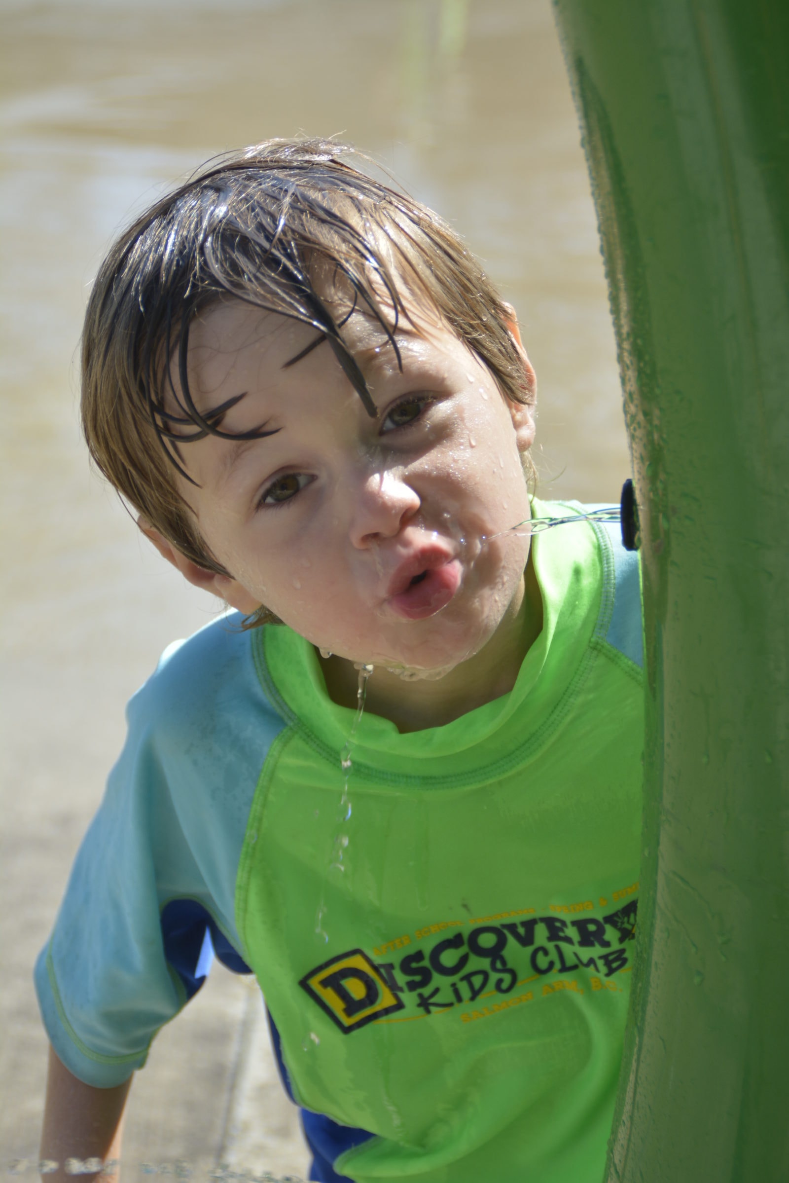 A Discovery Kids Club child having fun in the water wearing a club shirt