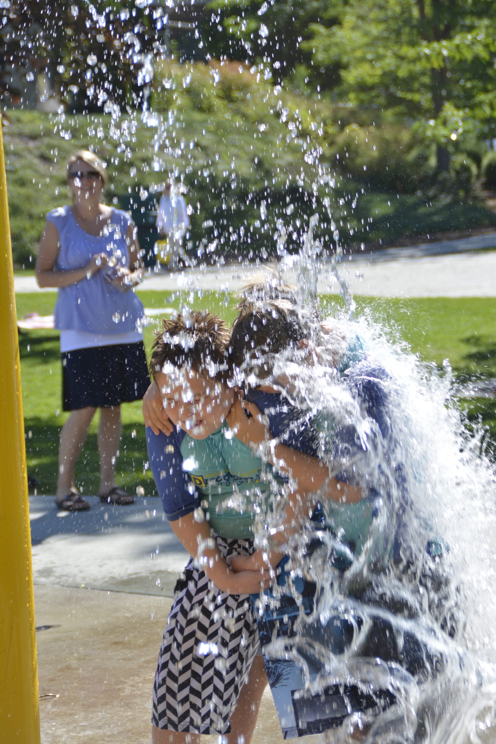 Kids getting soaked at the splash pad on a Discovery Kids Club outing