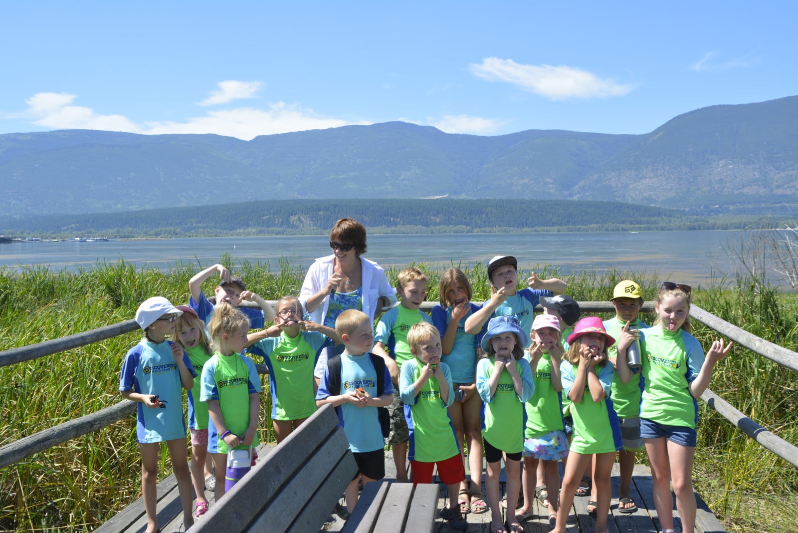 Discovery Kids Club group with Teena and kids by the school bus ready for an outing