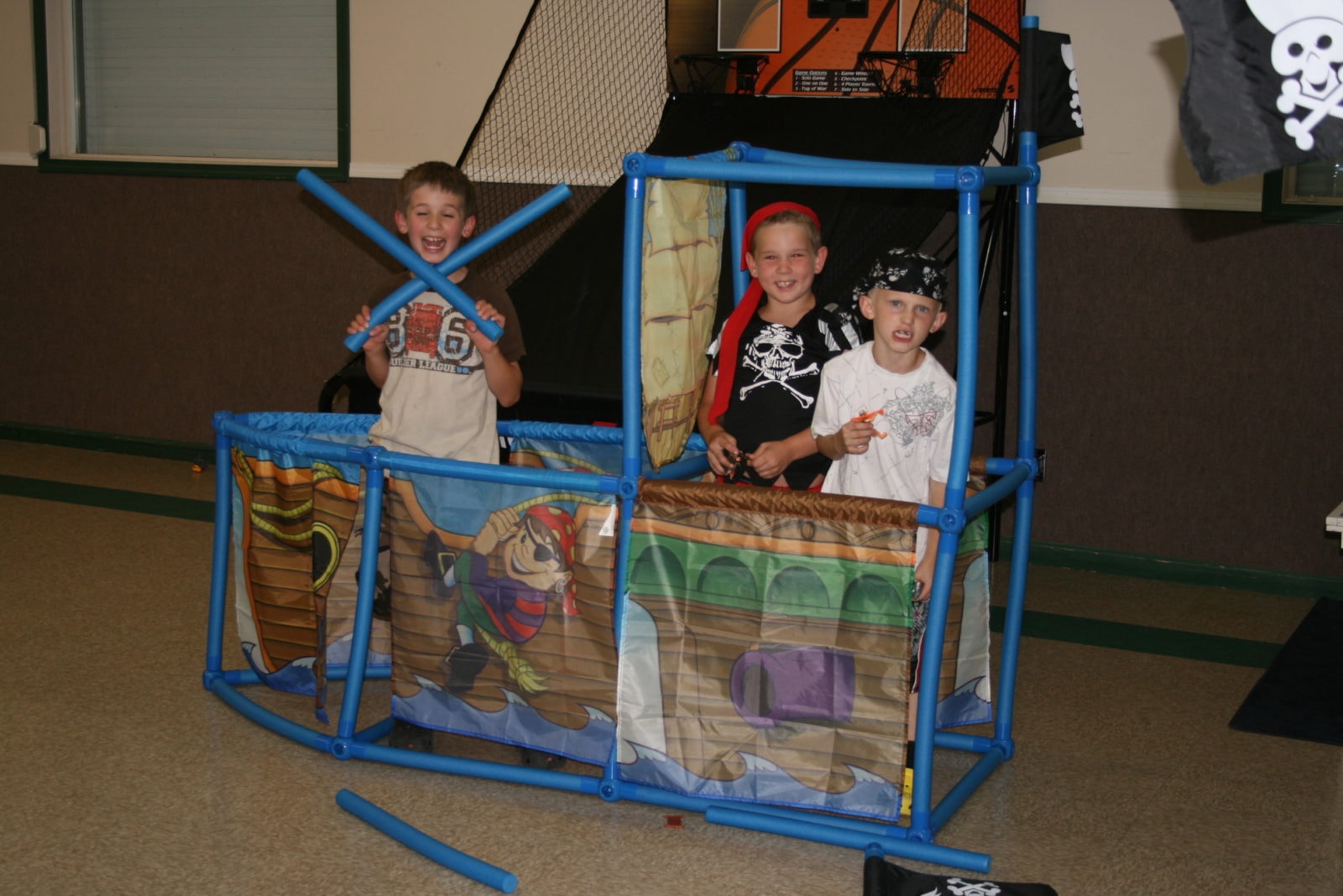 Three boys having a blast playing in a pirate ship play structure at Discovery Kids Club
